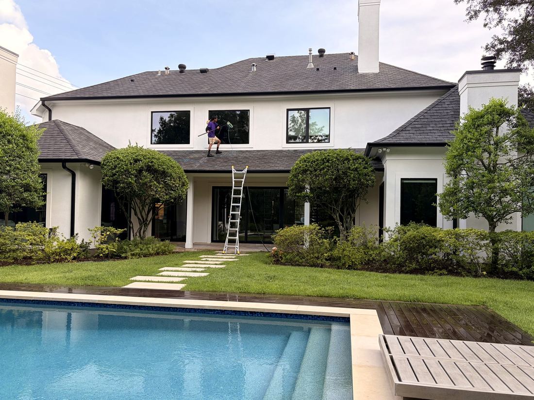 Our crew cleaning second-story windows above a Houston pool — safely from the roofline